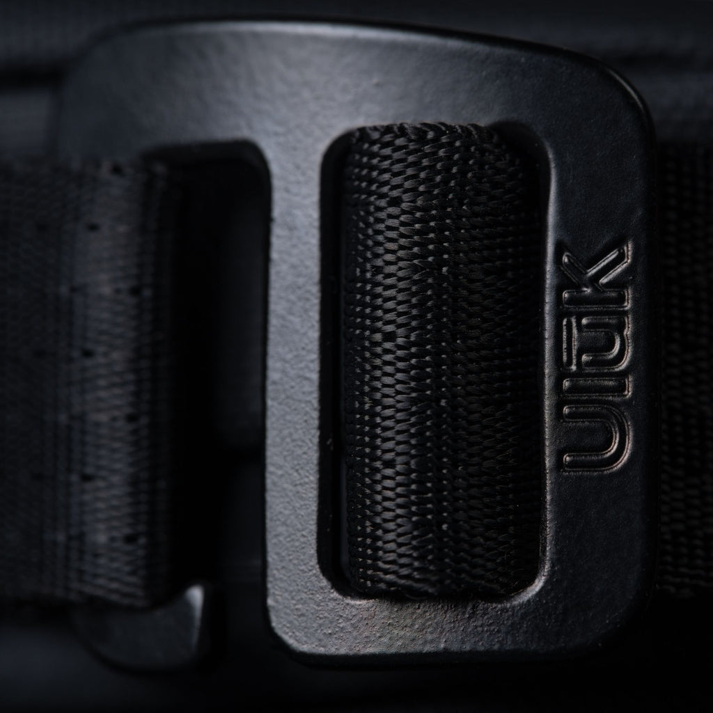 Extreme close-up of the black metal adjustment buckle with the Ulūk logo.