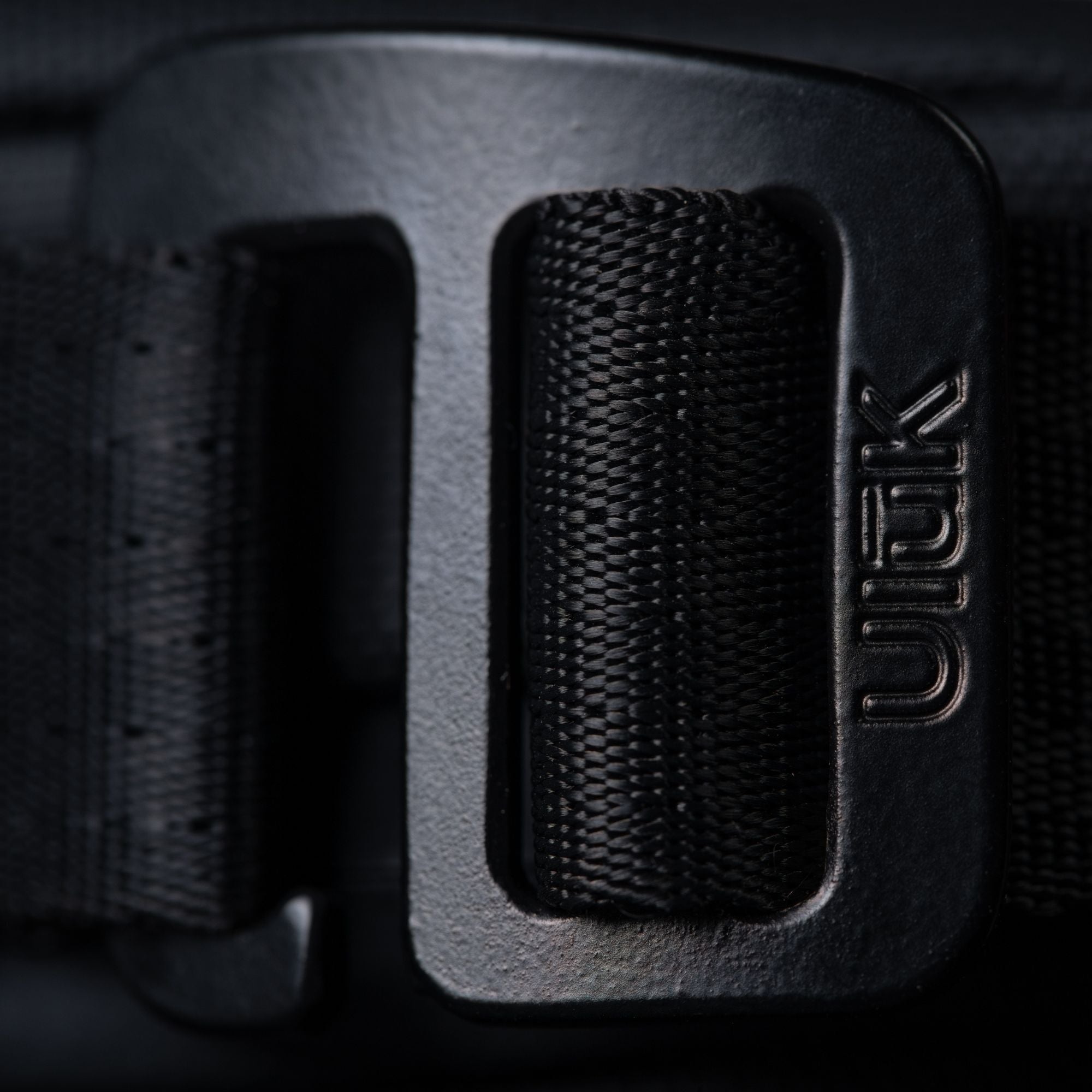 Extreme close-up of the black metal adjustment buckle with the Ulūk logo.