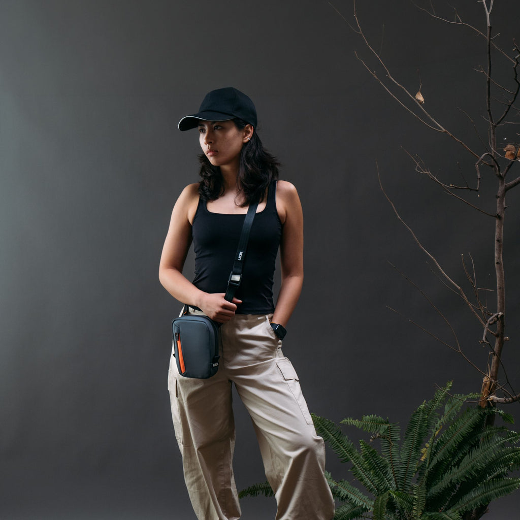 A model standing outside while wearing the slate gray microsling bag.